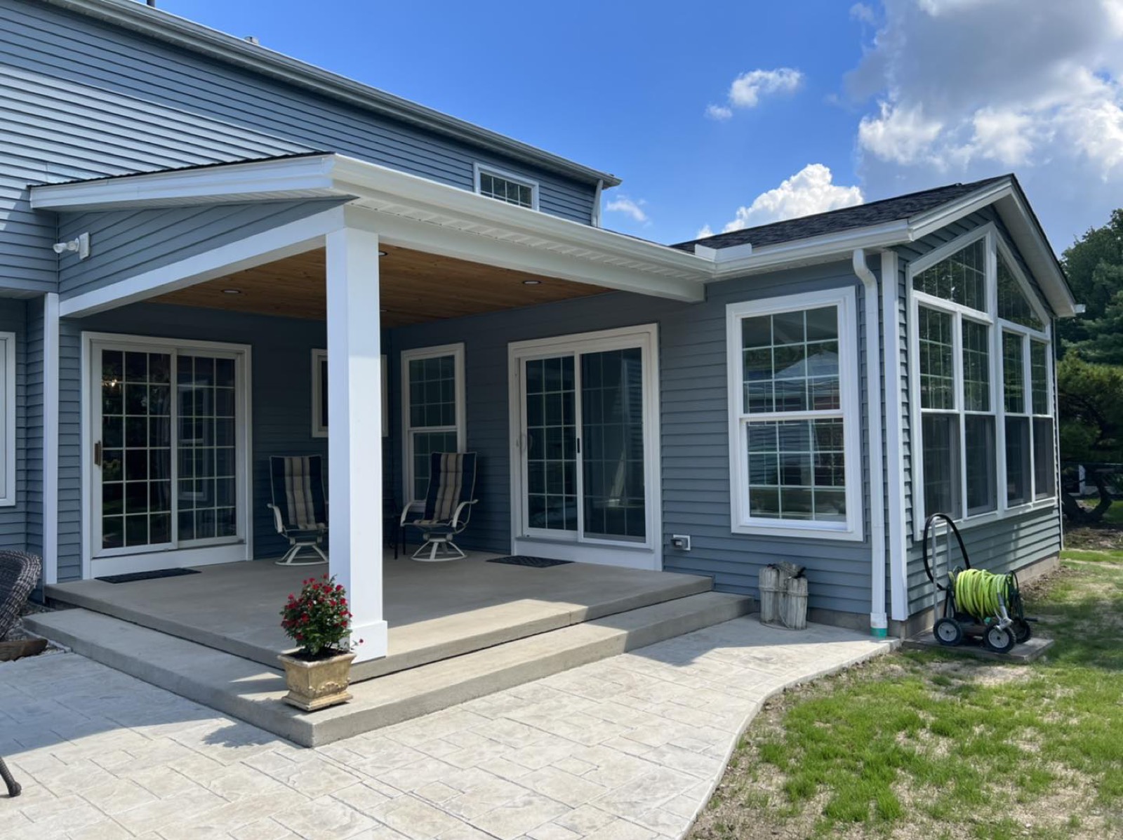 A blue-grey colonial home with a covered front porch, new siding and windows by R. Hammond Construction
