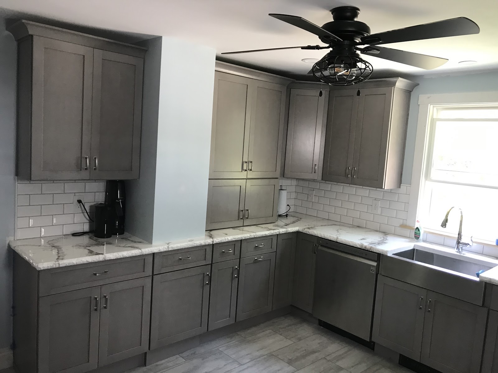 Remodeled kitchen with grey cabinets and a corner window
